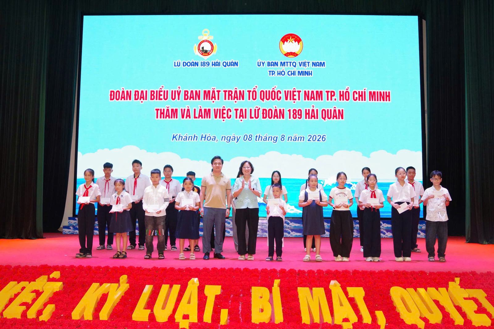 Người viết (đứng giữa) trao quà cho con em cán bộ, chiến sĩ Lữ đoàn 189 Hải quân, ngày 8-8-2026.